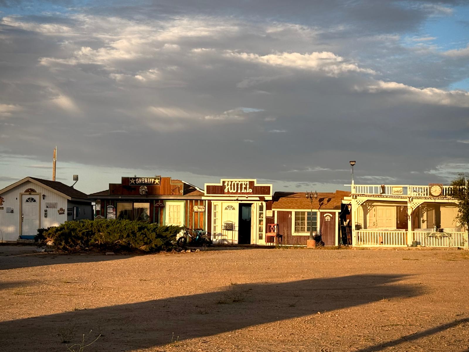 The Hikertown strip — schoolhouse, sheriff, hotel and cafe — in low gold light